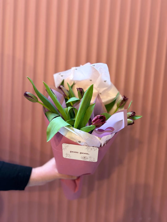 Weekly special lilac and white tulip wrap held against a terracotta wall