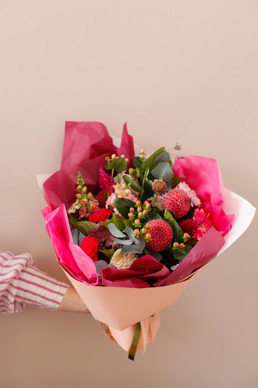 Hand-held Seasonal Lovers bouquet of red roses in pink wrap