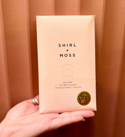 Hand holding a Shirl + Moss chocolate bar in pink packaging