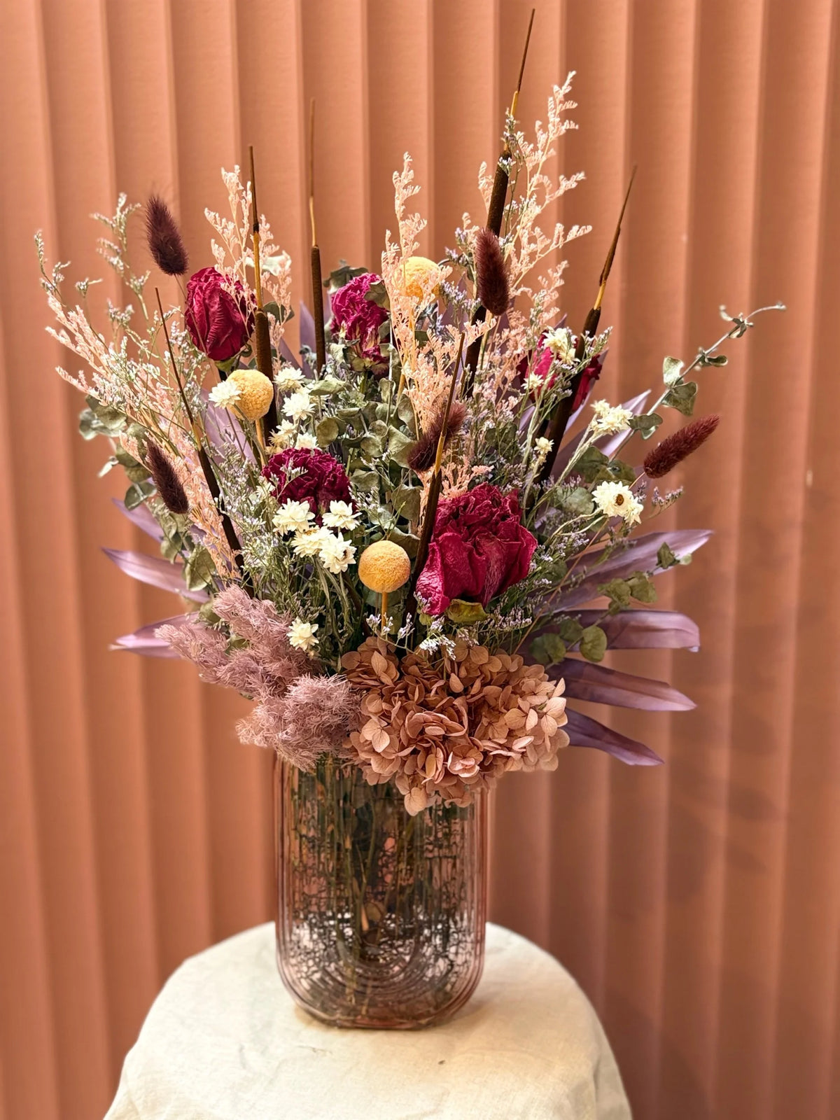Rainbow dried flowers in a glass vase with burgundy and cream tones