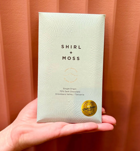 Hand holding a Shirl + Moss chocolate bar in green packaging