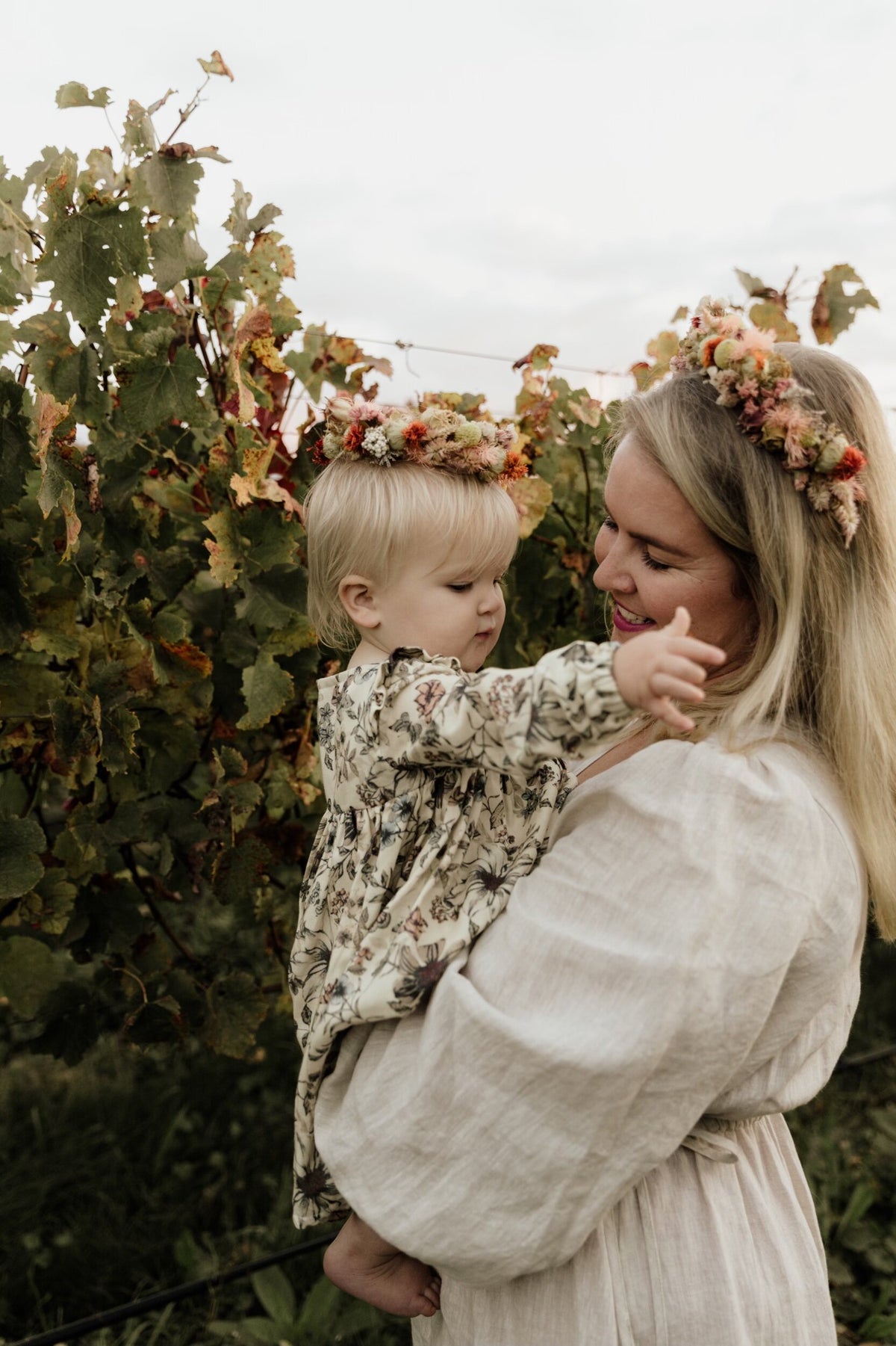Mother and daughter both wearing dried flower crowns outdoors