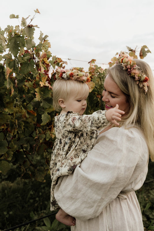 Mother and daughter both wearing dried flower crowns outdoors