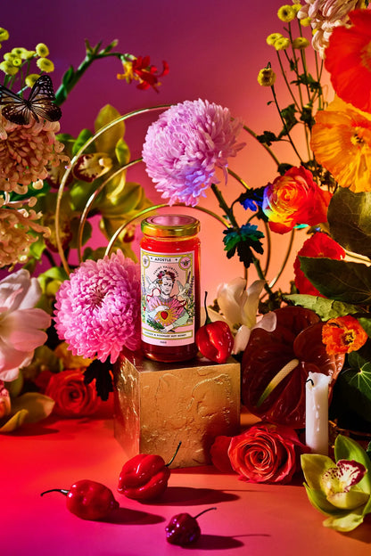Apostle hot honey jar styled with bright pink and red flowers