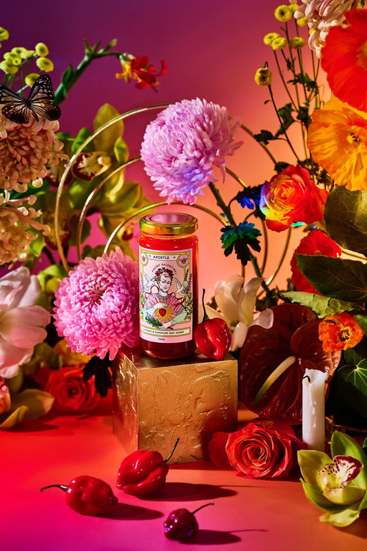 Apostle hot honey jar styled with bright pink and red flowers