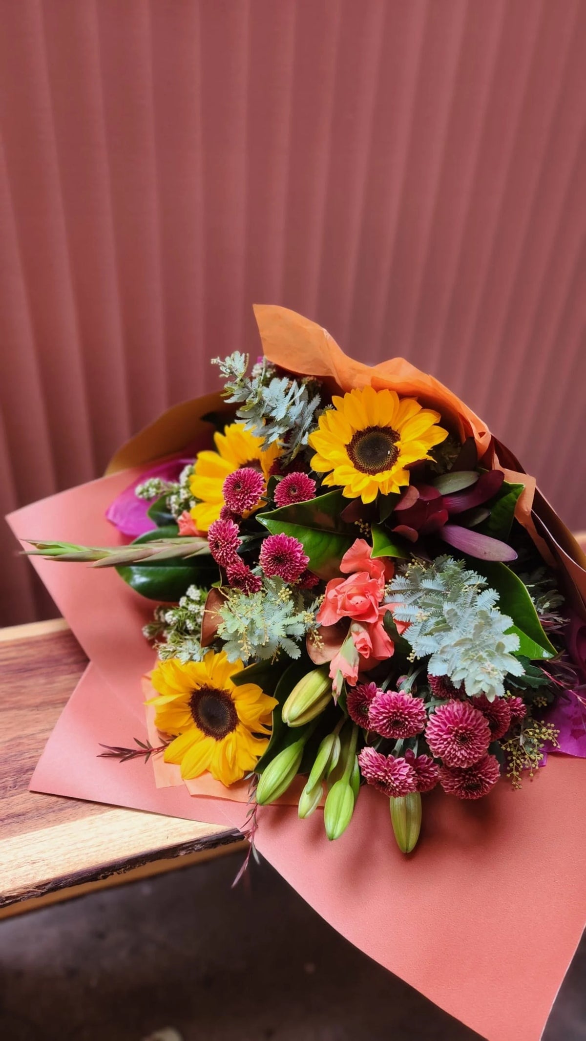 Seasonal bouquet with sunflowers and pink blooms in pink wrap