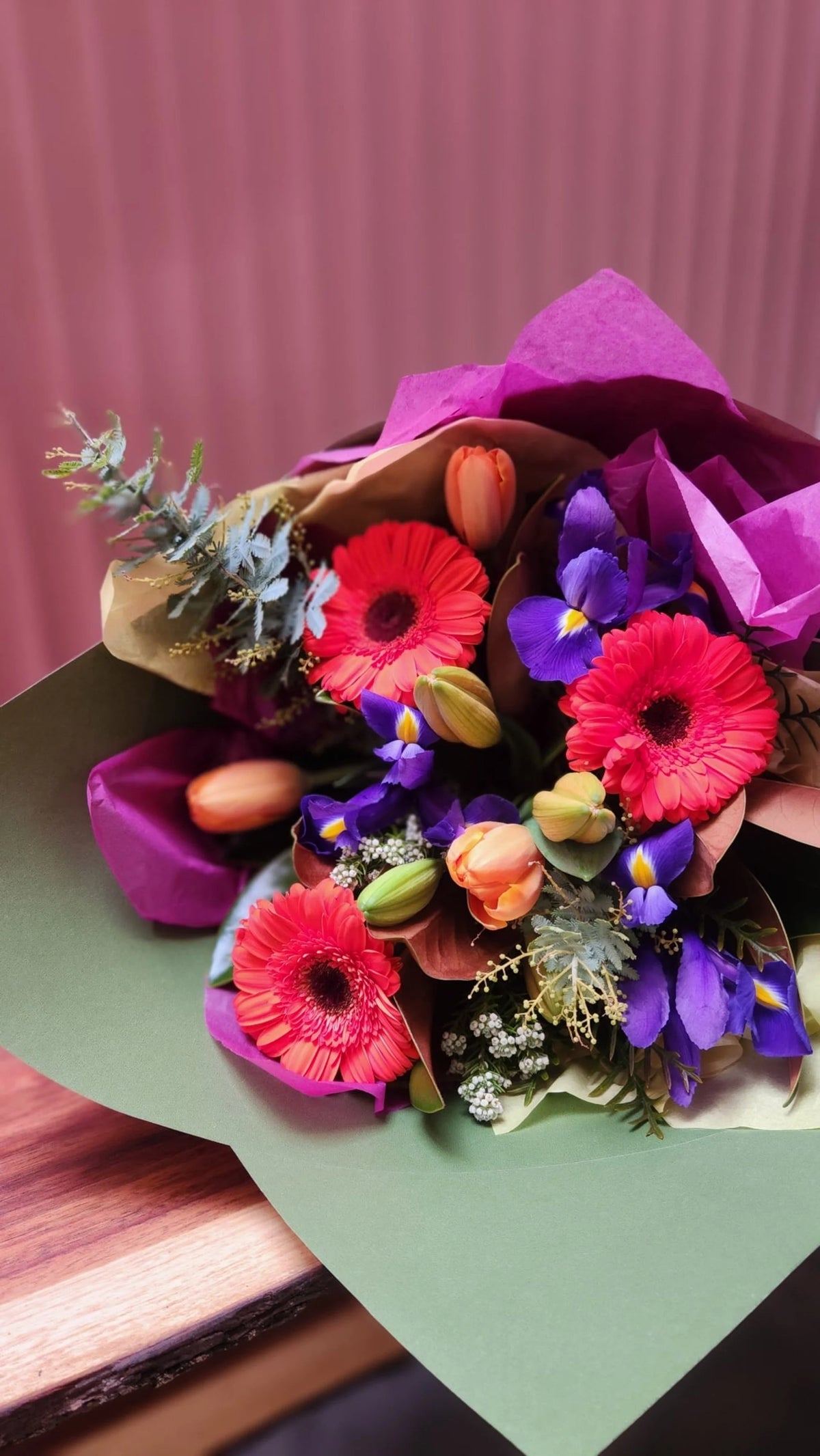Bright seasonal bouquet with gerberas and iris in green wrap