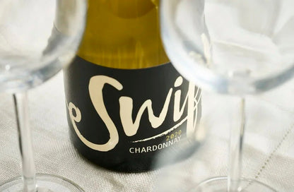 Close-up of the Swift Wines Chardonnay label with wine glasses
