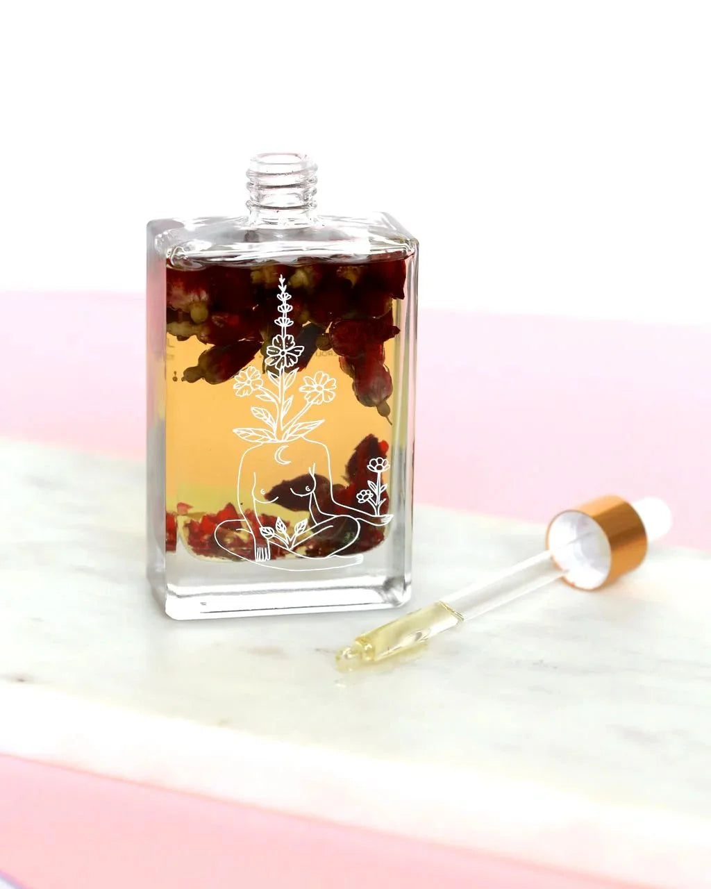 Self Love body oil with dried flowers and dropper on marble