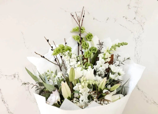Classic whites and greens bouquet with lilies and branches on marble